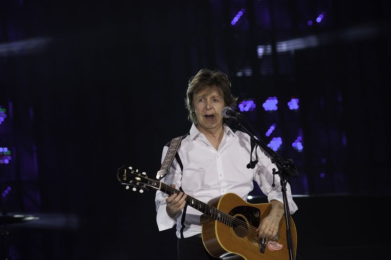 Paul McCartney playing guitar at a concert