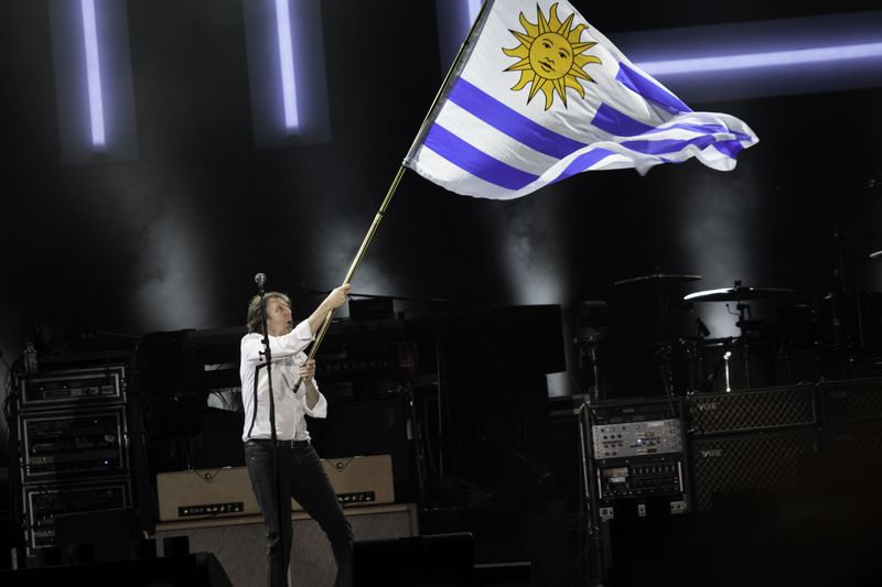 Paul McCartney performing with his band on stage