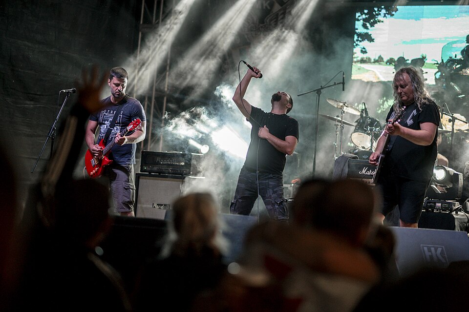 Live rock band performing at outdoor music festival with vibrant stage lights